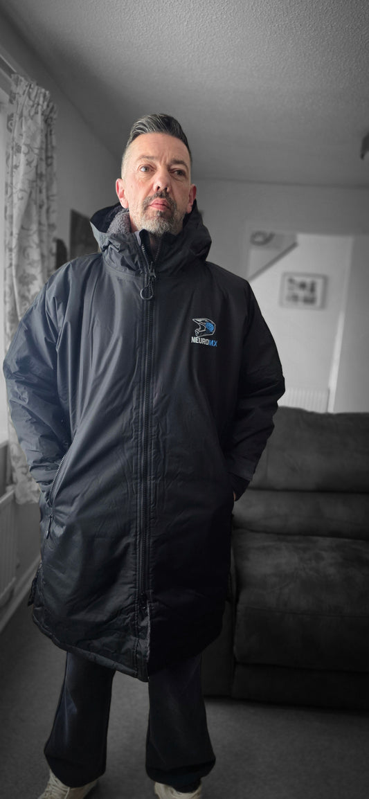 Man wearing black NeuroMX motocross parka jacket indoors, logo visible on chest