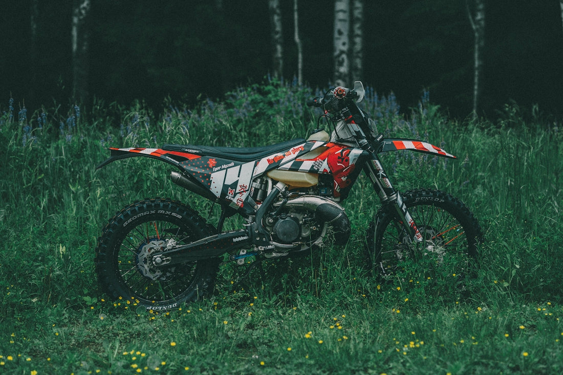 red and black motocross dirt bike on green grass field during daytime