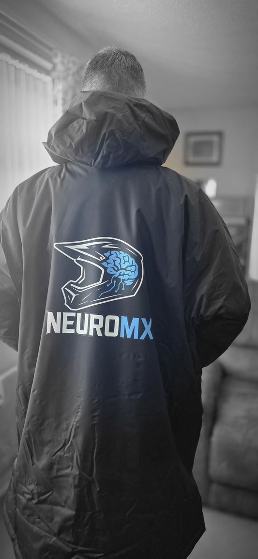 Person wearing black motocross jacket with helmet and brain graphic, NEUROMX logo on back